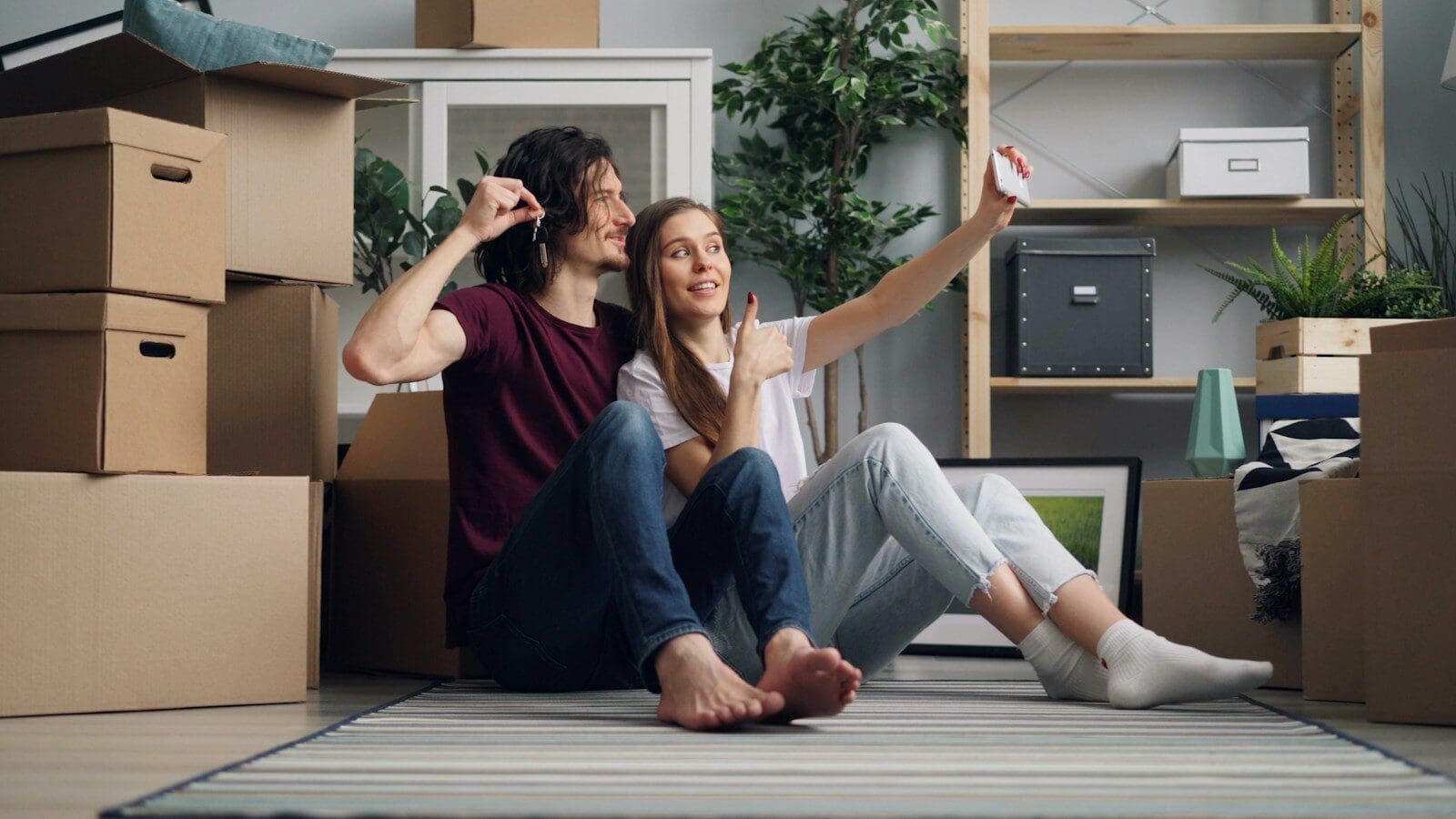 a man and a woman sitting on the floor in a room with moving boxes